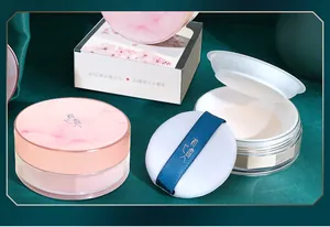 Détail d'une poudre libre fixatrice avec couvercle en marbre rose et houppe douce.