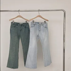 Dettaglio di jeans svasati blu chiaro e verde retrò su un appendiabiti in metallo