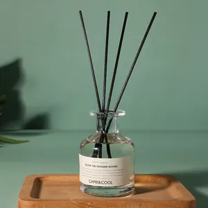 Eleganter Reed-Diffusor mit schwarzen Faserstäben in einer Glasflasche auf Holztablett