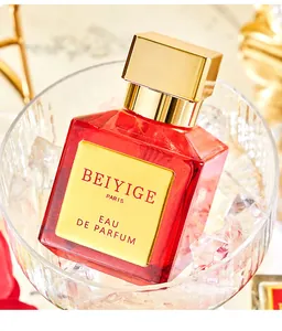 Elegante boccetta di profumo quadrata in vetro rosso con tappo dorato in una ciotola
