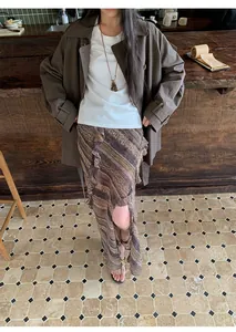 Vue en pied d'une femme portant un trench-coat marron à double boutonnage dans un café.