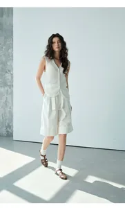 Full length fashion shot of a woman in a white mesh knit vest and shorts outfit
