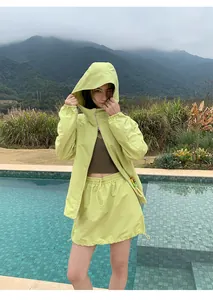 Sportieve outdoor outfit met lichtgroene windbreaker en bijpassende mini-rok met trekkoord.