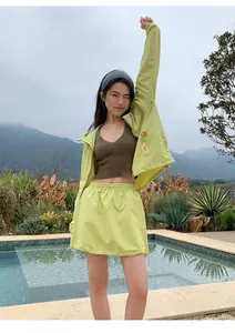 Model poseert in een limegroene outdoor rok met trekkoord bij een prachtig zwembad