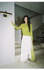 Full body shot of white irregular long tiered cake skirt on Asian model in interior.