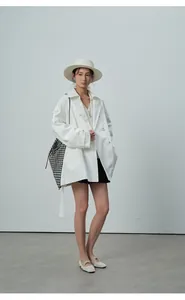 Vue complète d'une femme en trench-coat blanc à double boutonnage avec un chapeau