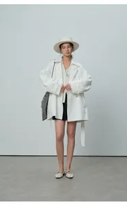 Vue en pied d'un trench-coat blanc à double boutonnage au style minimaliste chic