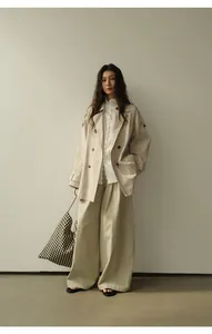Vue en pied d'un trench-coat beige classique à double boutonnage et pantalon large