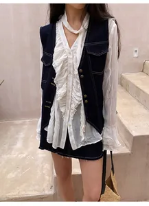 Gilet en jean vintage élégant avec surpiqûres contrastées sur un chemisier blanc à volants