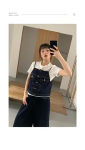 Dettaglio di un gilet in denim blu scuro indossato sopra una maglietta bianca in un selfie.