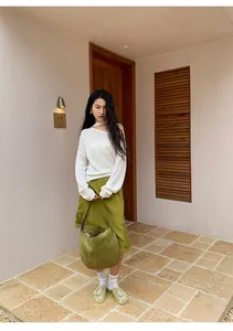 Modelo con falda verde irregular con encaje y top de punto blanco en un entorno exterior