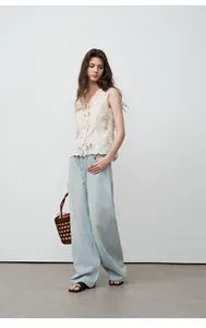 Femme portant un jean large et droit bleu clair avec un haut en dentelle en studio