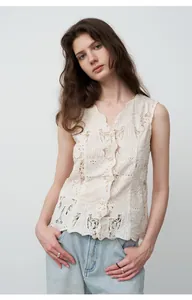Vue détaillée d'un gilet en dentelle brodée avec un jean droit bleu clair chic.