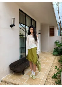 Modelo con falda midi verde irregular con encaje y top blanco con hombros caídos