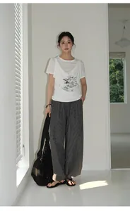 Full body model view of retro plaid wide-leg trousers in a minimalist room setting