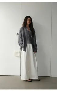 Stylish woman wearing retro white wide-leg trousers paired with a dark grey denim shirt.