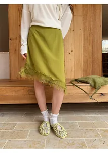 Vista detallada de una elegante falda midi asimétrica verde con ribete de encaje fino