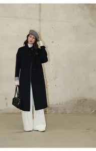 Mannequin asiatique portant un pantalon large blanc et un long manteau en laine noir en studio