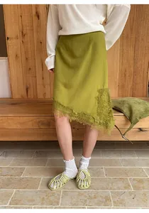 Detalle de falda midi verde con dobladillo irregular, encaje y sandalias tejidas moda