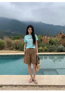 Stylish woman wearing casual brown linen wide-leg shorts with a belt by a luxury pool