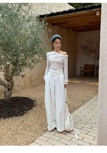 Full-length shot showing the flowy fit of white wide-leg trousers in a garden.