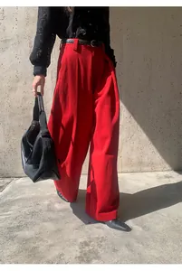 Gros plan sur un pantalon large rouge brossé avec ceinture noire et haut en dentelle.