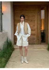 Women's white linen wide-leg shorts styled with a vest in a leisure setting.