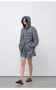 Full-length view of woman in blue and green plaid hooded jacket and matching shorts