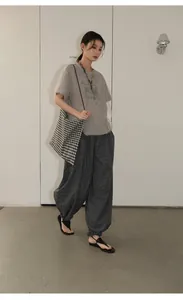 Model wearing vintage plaid loose pants and matching tote bag in minimal studio