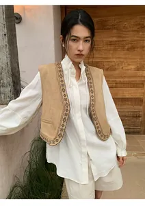 Asian model styling off-white linen wide-leg shorts with an ethnic embroidered tan vest.