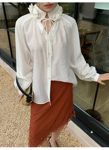 Detalle de falda midi terracota con dobladillo de encaje y blusa blanca con flores