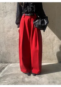 Texture et drapé du pantalon large rouge à taille haute porté avec une ceinture tressée.