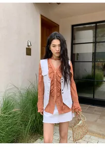 Gilet en jean blanc à surpiqûres contrastées et chemisier à volants orange en gros plan