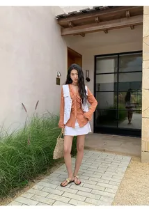 Gilet en jean blanc rétro avec coutures contrastées sur chemisier orange et jupe.
