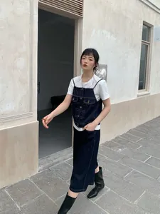 Modella che indossa canotta in denim blu scuro sopra una t-shirt bianca stile street