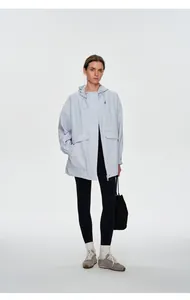 Vue en pied d'une femme en veste techwear bleu clair avec capuche et poches utilitaires