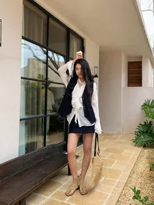 Gilet en jean vintage avec surpiqûres contrastées et chemisier blanc à volants.