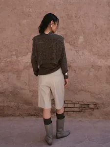 Elegant beige PU leather wide-leg Bermuda shorts for women in a rustic outdoor setting