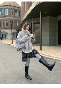 Detail view of grey warm thermal leggings styled with plaid skirt and black boots.