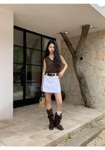 Outdoor fashion photo of a women's brown V-neck knit vest with a white denim skirt