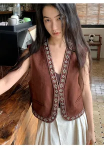 Detailansicht einer braunen Weste im Vintage-Stil mit aufwendiger weißer Stickerei