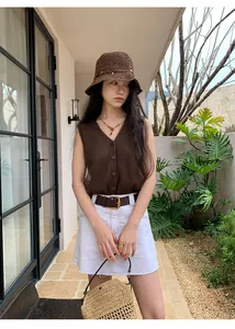 Close-up detail of a brown mesh patchwork knitted vest with buttons on a model outdoors