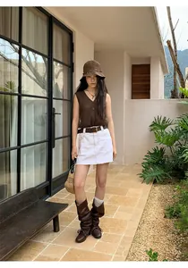 Professional outdoor fashion photography of a brown knit vest and white skirt.