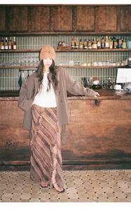 Détail d'un trench-coat croisé marron pour femme dans un décor de bar rétro chic