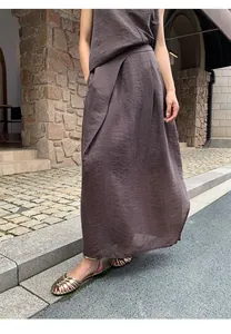 Detailed view of a dark brown irregular pleated midi skirt with crinkle fabric texture