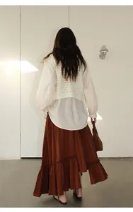 Back view of an irregular tiered long brown skirt featuring a minimalist layered design
