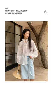 Model wearing a white floral collar blouse and a light blue denim skirt in a natural setting