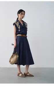 Full body view of a navy sleeveless lapel dress with waist belt and scarf accent