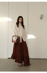 Visual detail of the tiered layers and irregular hem on a brown long skirt worn by model.