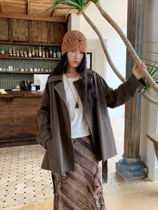 Mannequin portant un trench-coat marron à double boutonnage et revers dans un café
